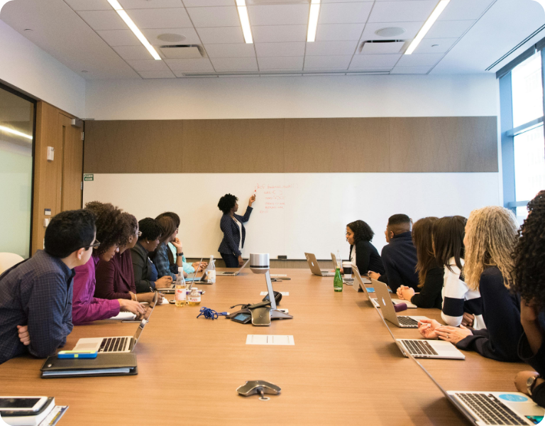 People in meeting with person at whiteboard